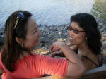 Vi and Thu Oanh sitting in the shade by the shore.